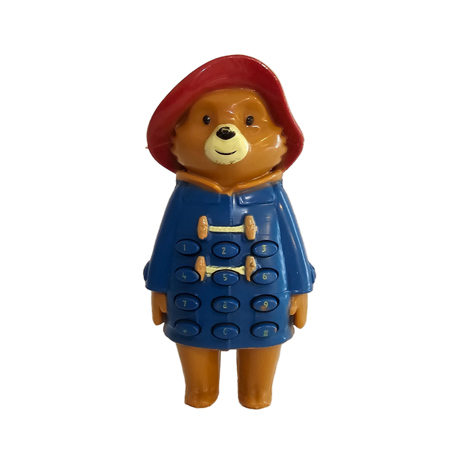 This image displays a vintage Paddington Bear push button figure, a collectible from the UK. Paddington, depicted in his iconic blue coat and red hat, stands upright on a white background.